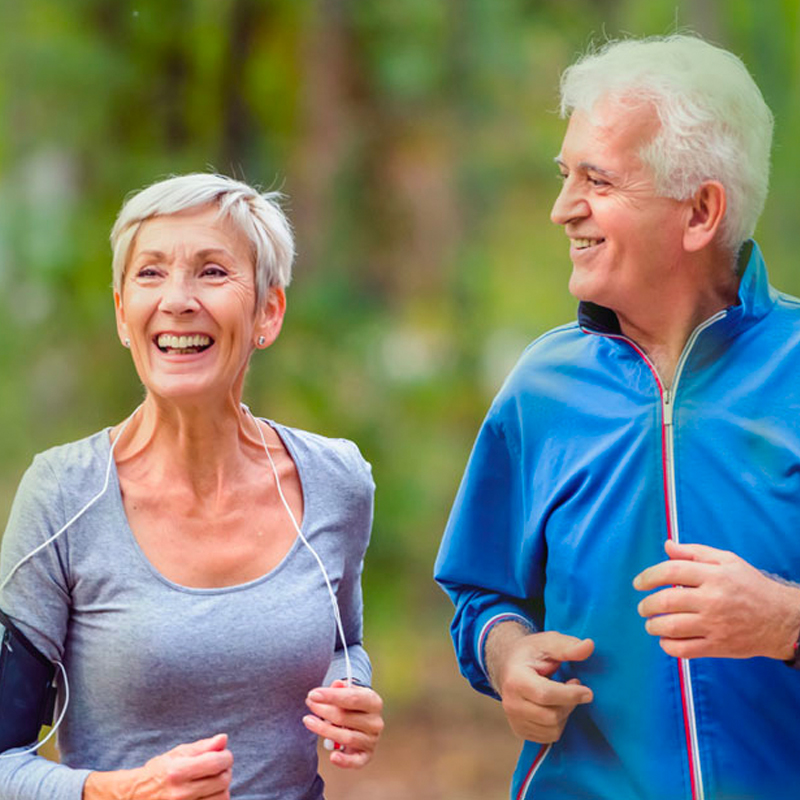 Elderly caucasian couple jogging in a wooded trail
