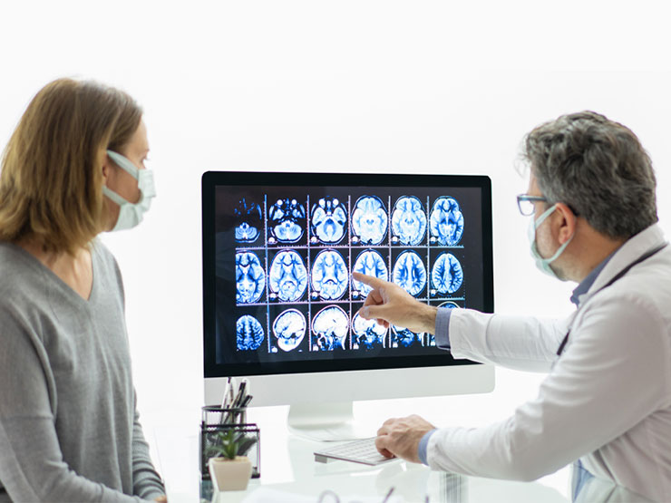 Doctor and patient look at xray images of a brain.