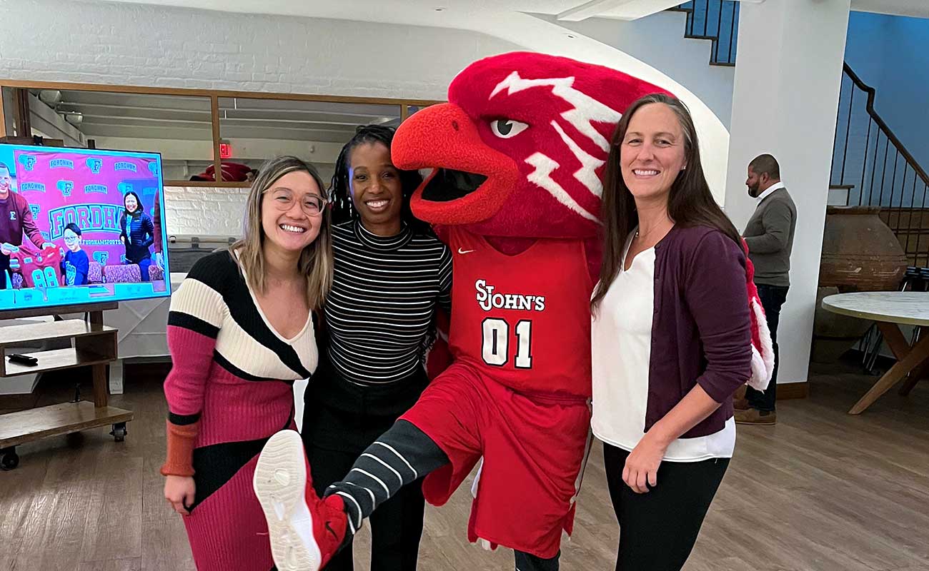 People posing with St. John's mascot, smiling at the camera