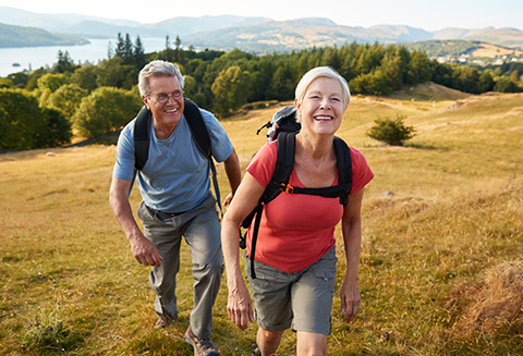Senior couple climbing a hill on a hike through the countryside