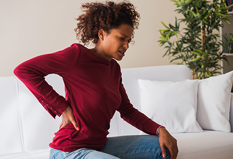 Woman in pain hold her lower back with her hand