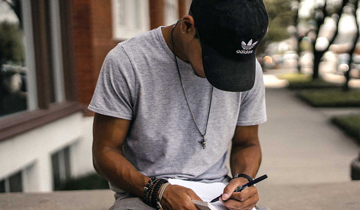 Teen sitting outside and writing in a notebook