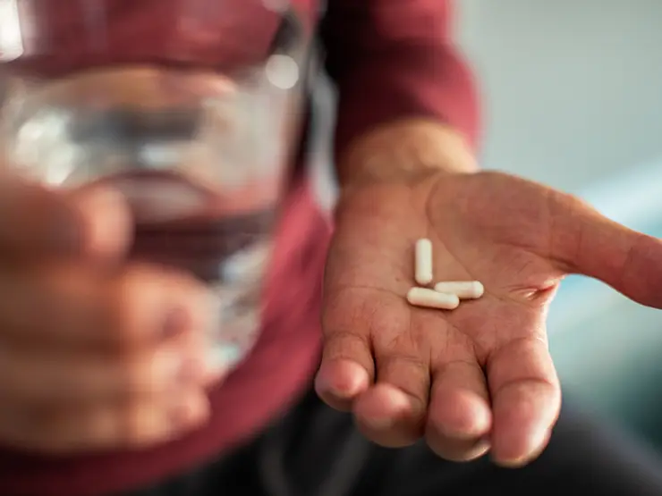 image of pills and glass of water in person's hands