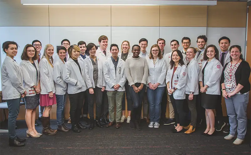 A group of men and women posting together in white medical coats