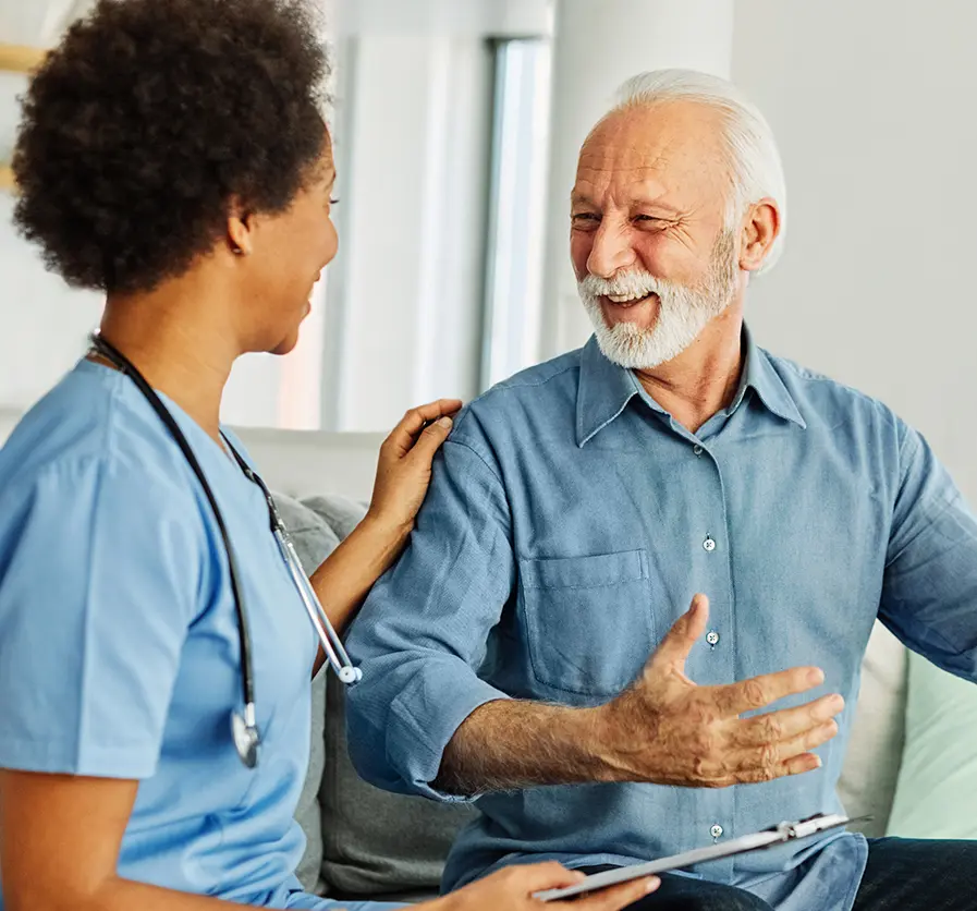 A nurse and an elderly patient greet each other