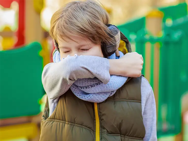 image of child coughing and sneezing into elbow