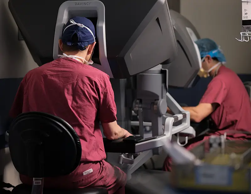 surgeons and trainee work side-by-side on a surgical robot