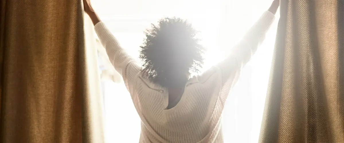 Woman drawing open curtains in the morning